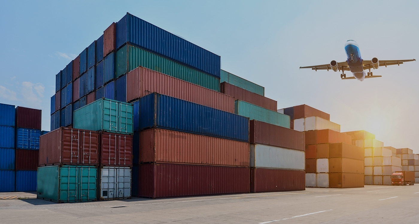 Airplane flying over a shipping container yard